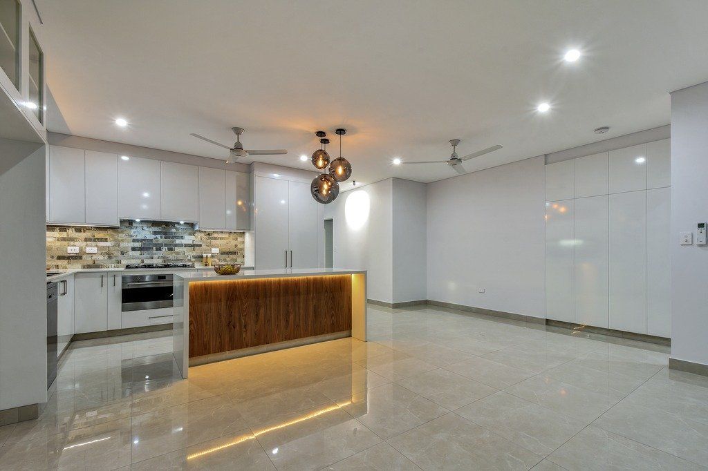 A large empty room with a kitchen and a large island in the middle.