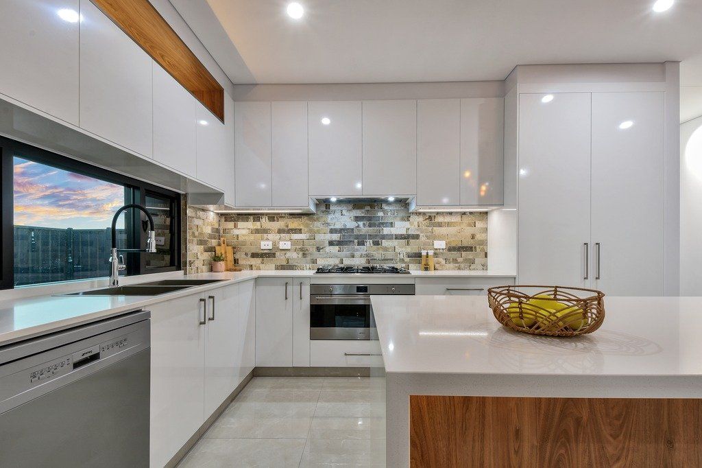 A kitchen with white cabinets , stainless steel appliances , and a large island.
