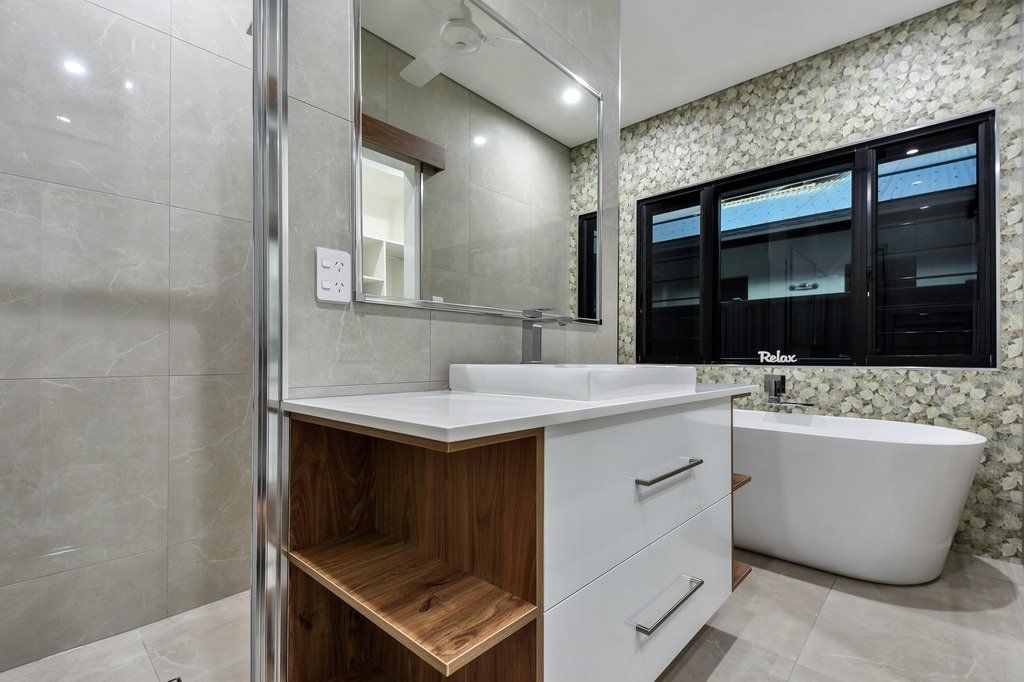 A bathroom with a sink , tub and mirror.