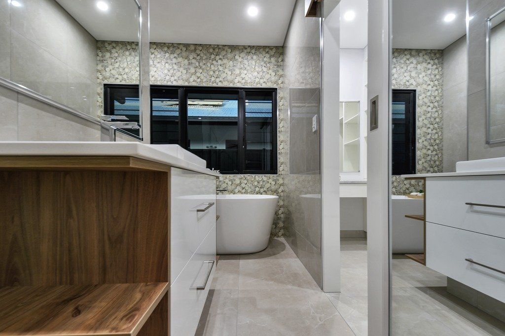 A bathroom with a tub , sink and mirror.