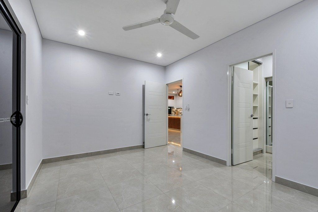 An empty room with a ceiling fan and a door leading to a bathroom.