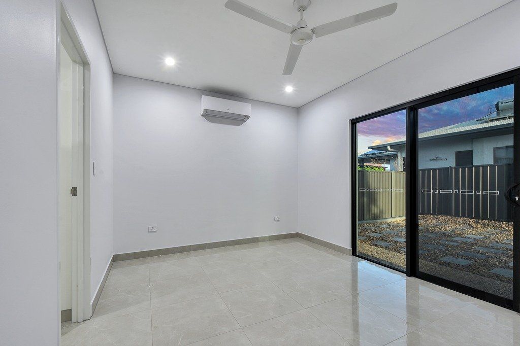 An empty room with a ceiling fan and sliding glass doors.