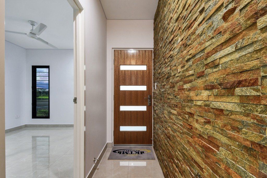 A hallway with a brick wall and a wooden door