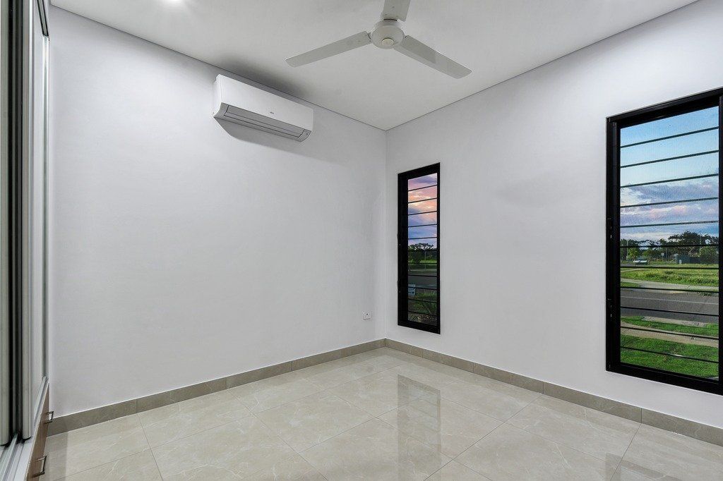 An empty room with a ceiling fan and two windows.