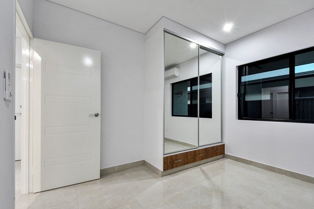 An empty room with a mirrored wardrobe and two windows