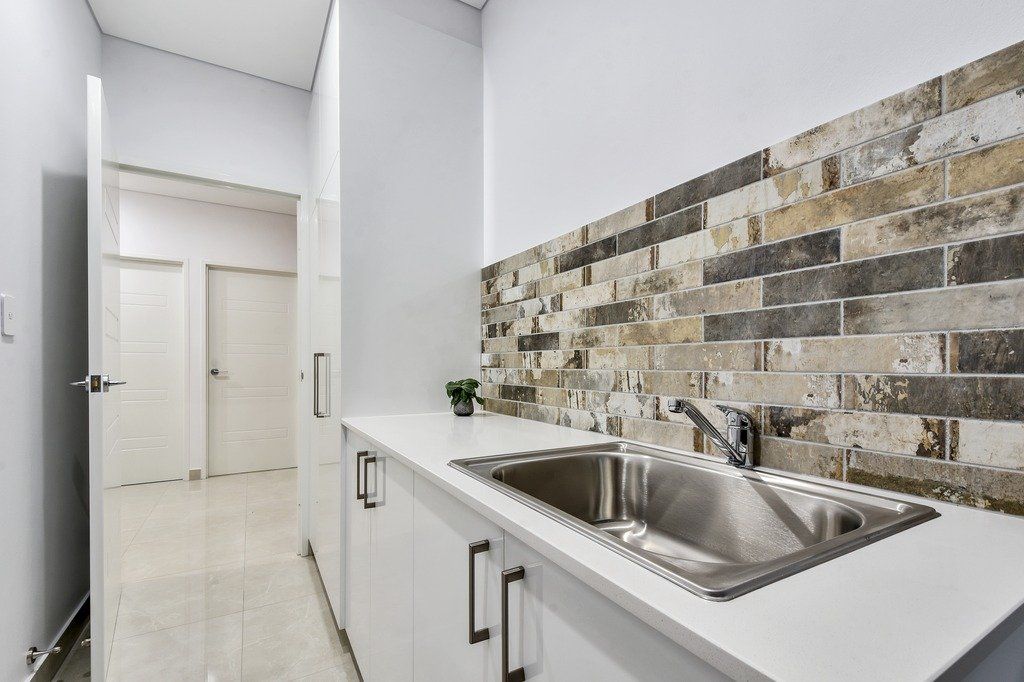 A kitchen with a sink and a brick wall