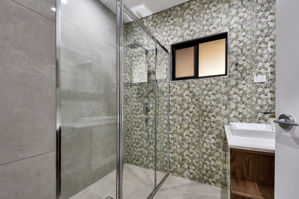 A bathroom with a walk in shower and a sink.