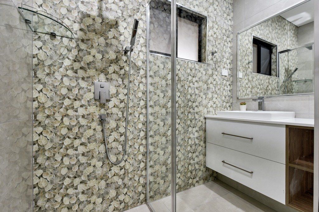 A bathroom with a walk in shower , sink and mirror.
