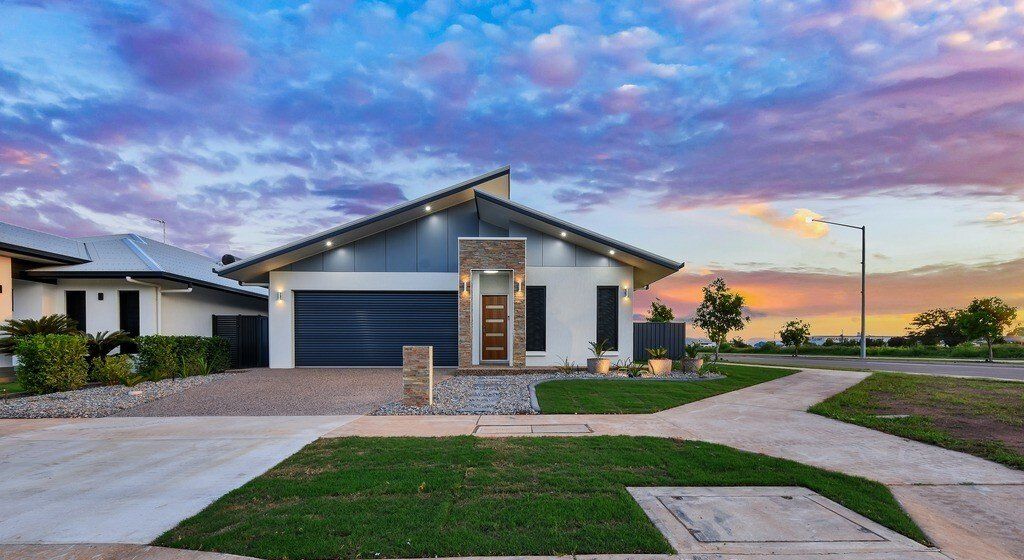 A white house with a blue garage door is sitting on top of a lush green lawn.