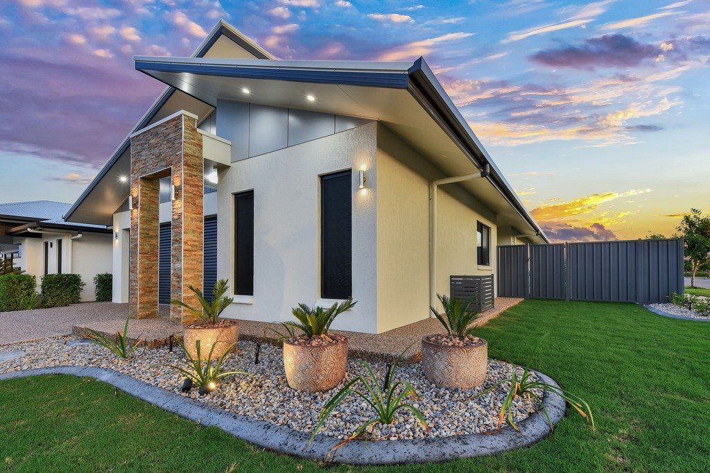 A large white house with a fence and a lush green lawn in front of it.