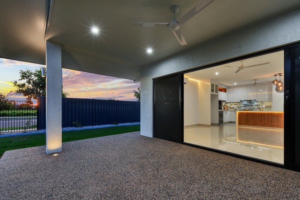 A large sliding glass door is open to a kitchen and patio area.