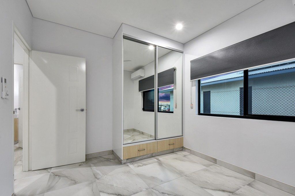 A bedroom with a large mirrored wardrobe and a window.