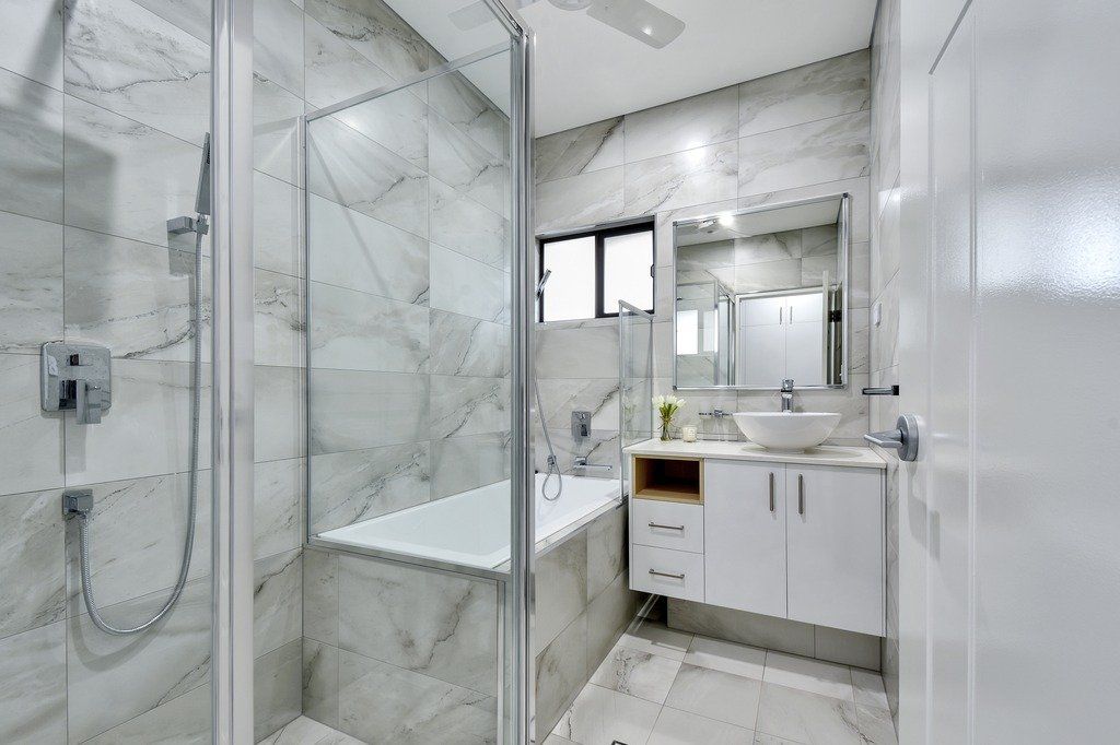 A bathroom with a bathtub , sink , shower and mirror.