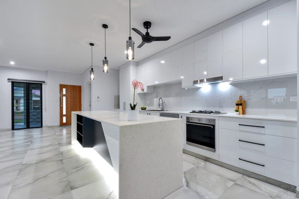 A kitchen with white cabinets and a ceiling fan