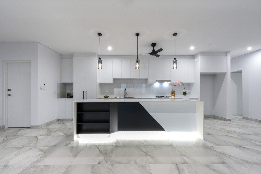 An empty kitchen with white cabinets and marble floors