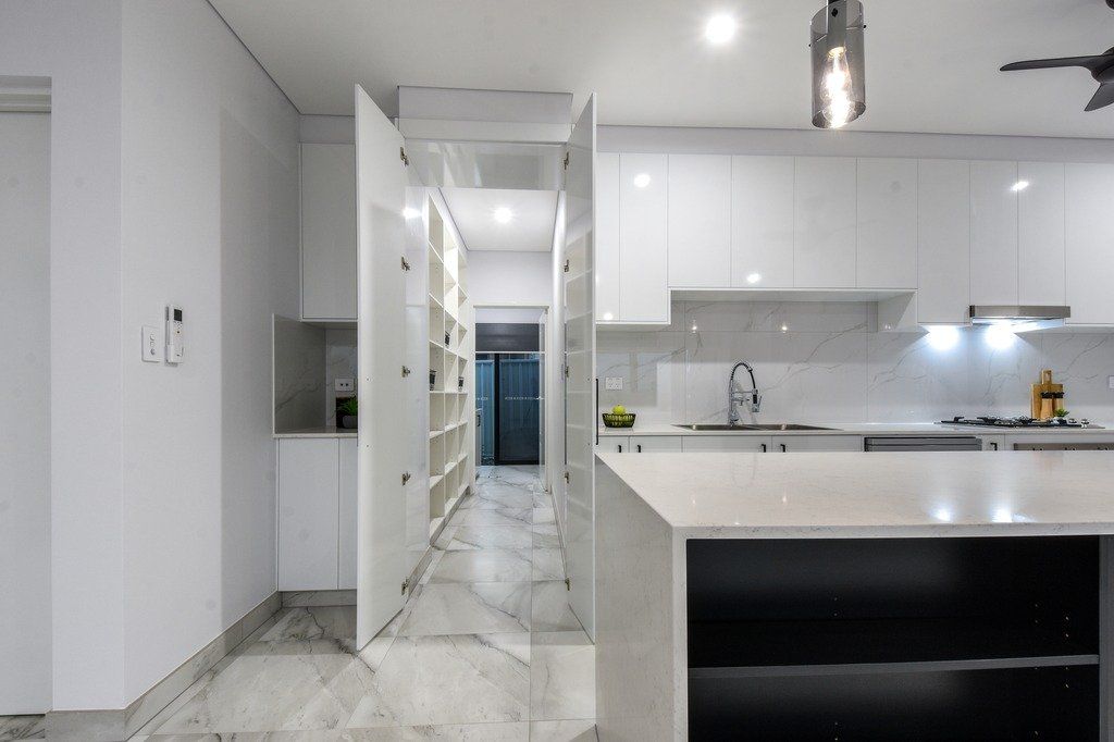 A kitchen with white cabinets and a black island.