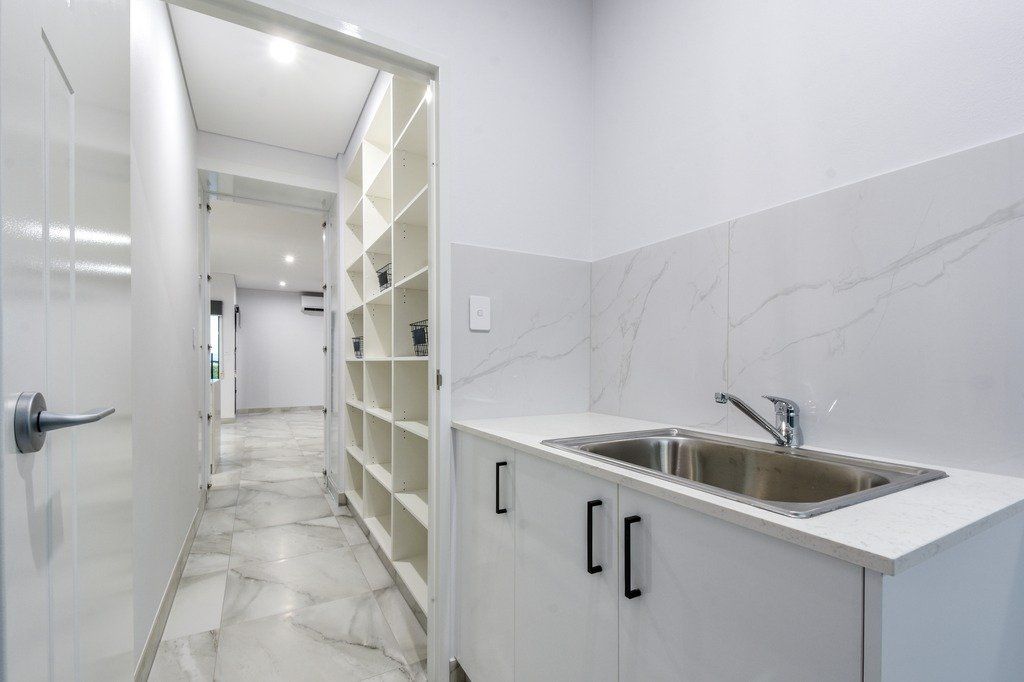 A kitchen with white cabinets and a sink in a hallway.