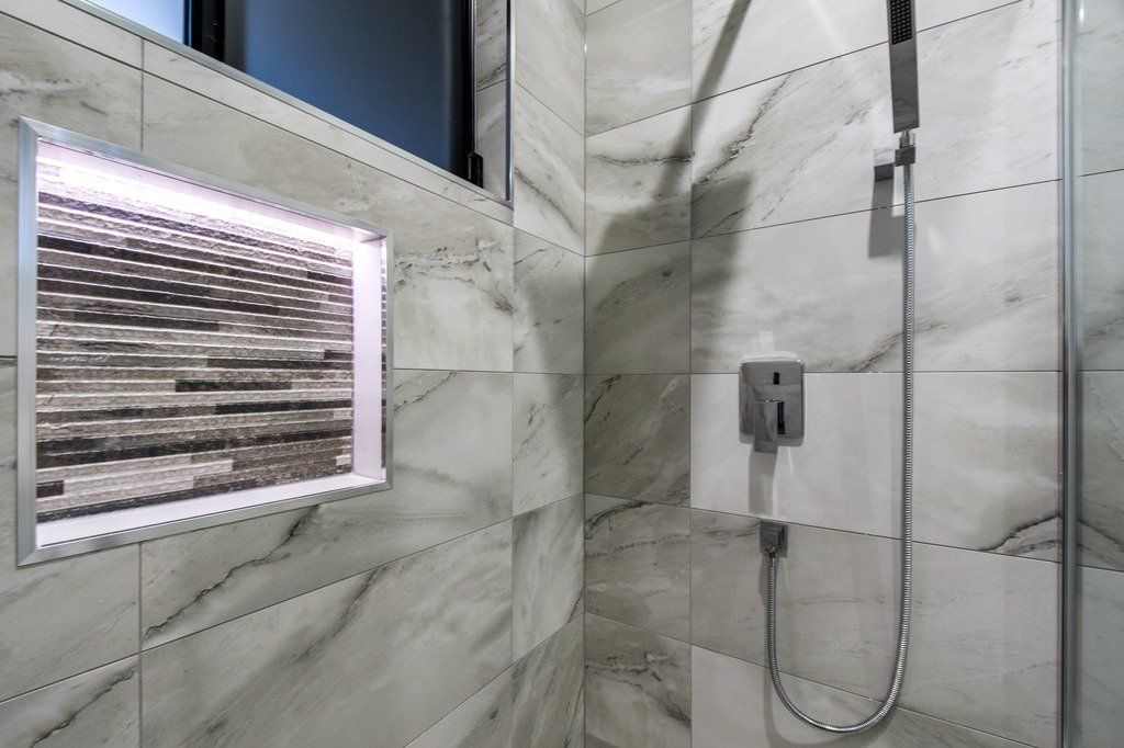 A bathroom with marble tiles and a shower head