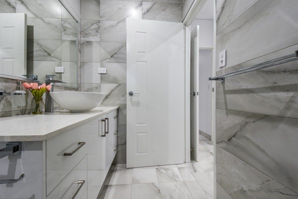 A bathroom with a sink , mirror and door.