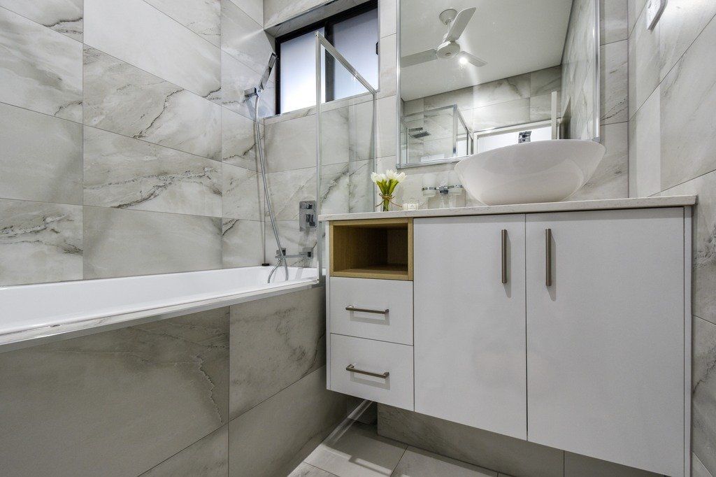 A bathroom with a bathtub , sink and mirror.