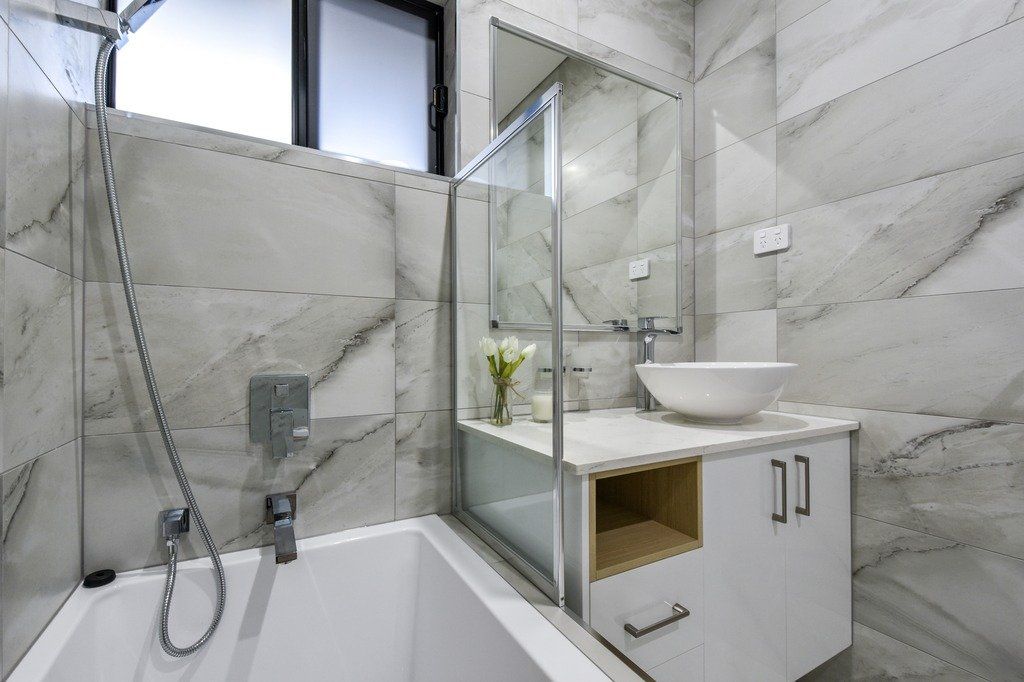 A bathroom with a bathtub , sink , mirror and shower.