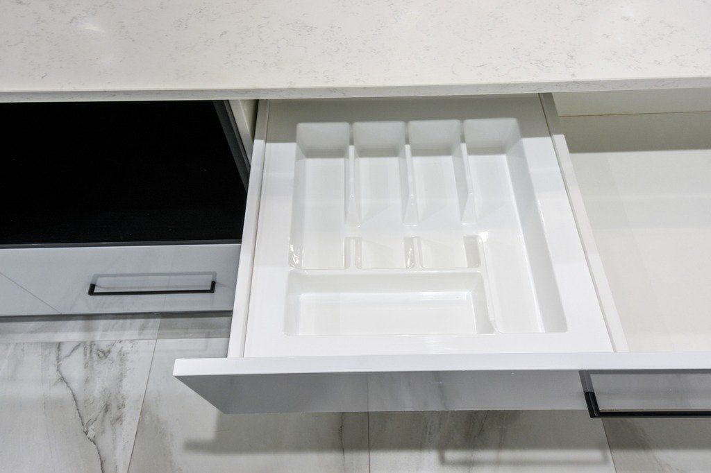 A white drawer filled with utensils in a kitchen.
