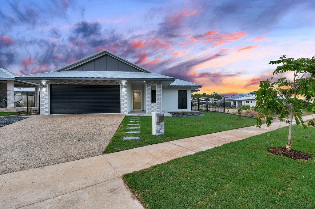 A large white house with a large driveway and a tree in front of it.