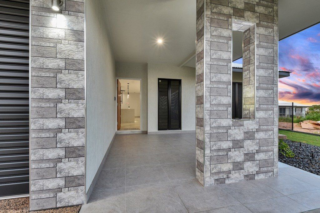 A brick walkway leading to a house with a sunset in the background.