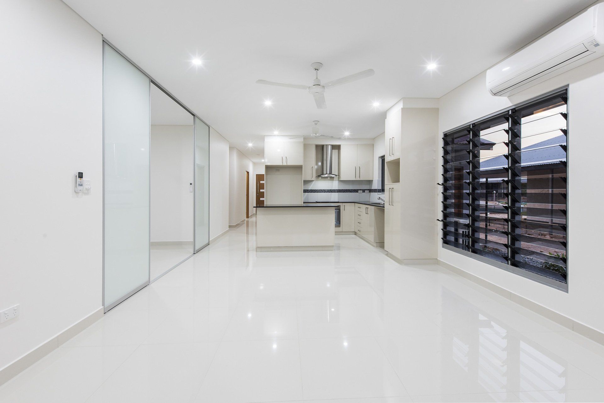 A large empty room with a kitchen and sliding glass doors