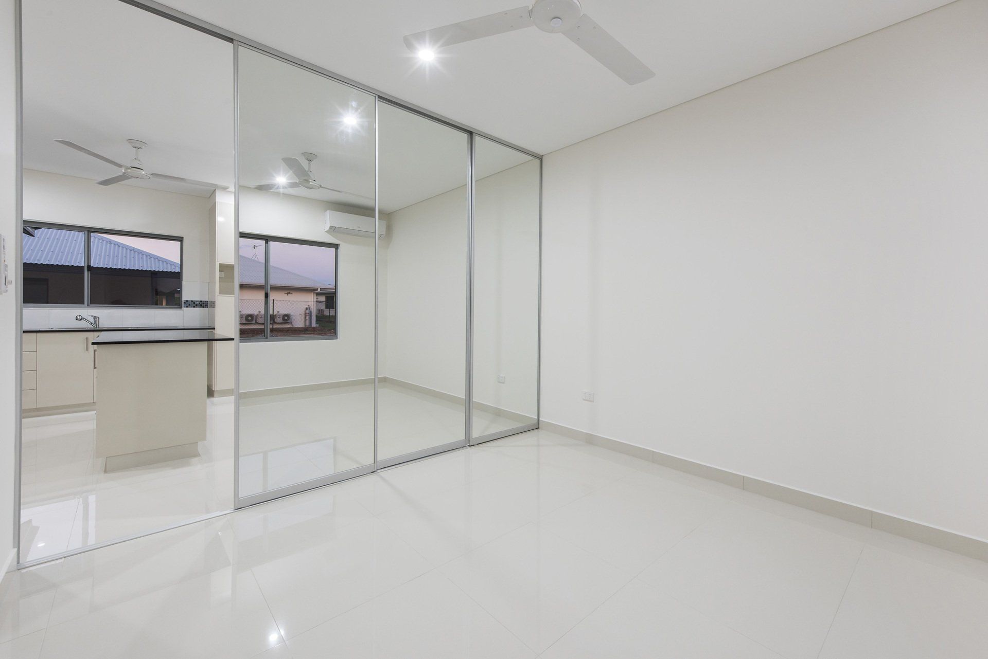 An empty room with sliding glass doors and a ceiling fan.