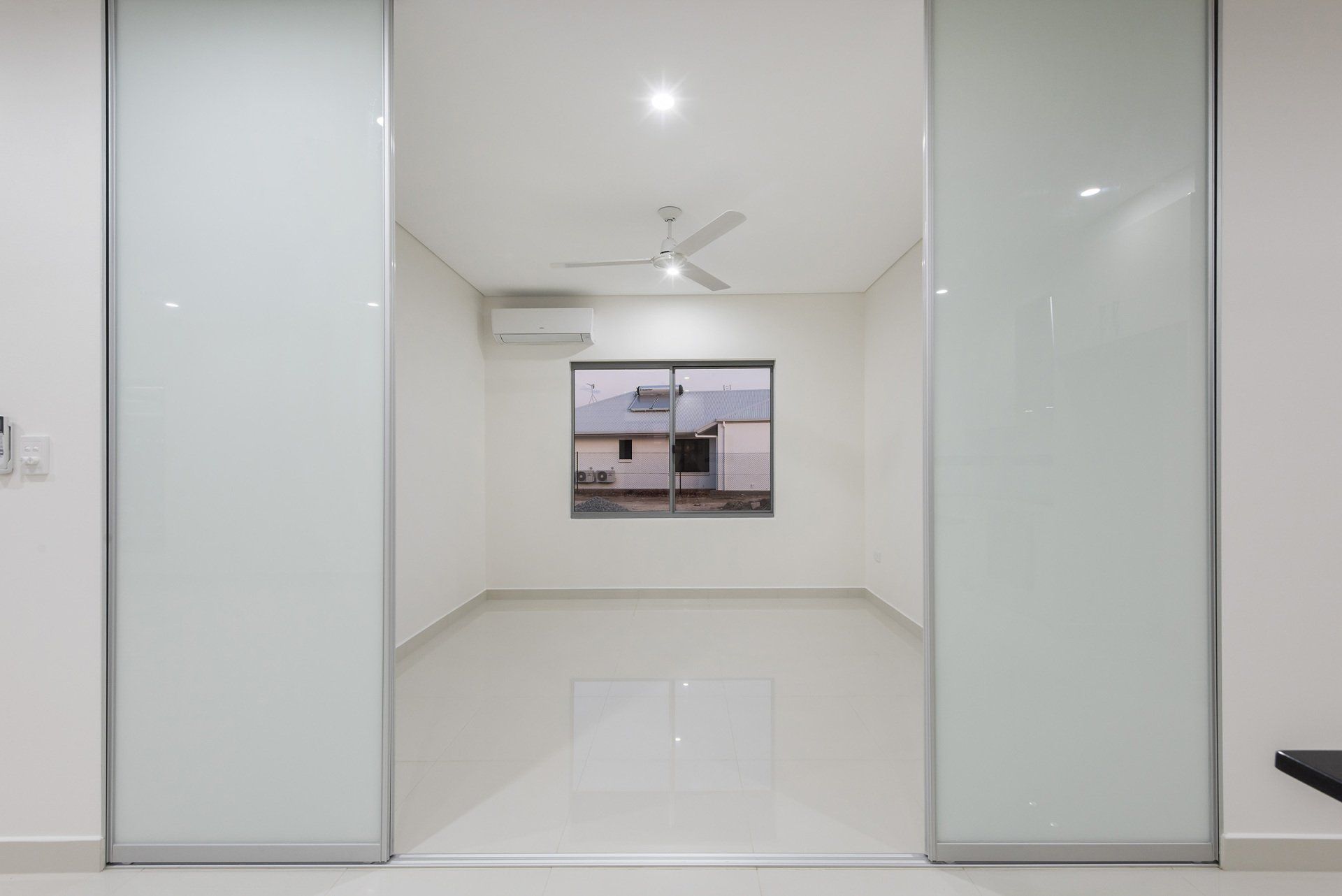 An empty room with sliding glass doors and a window.