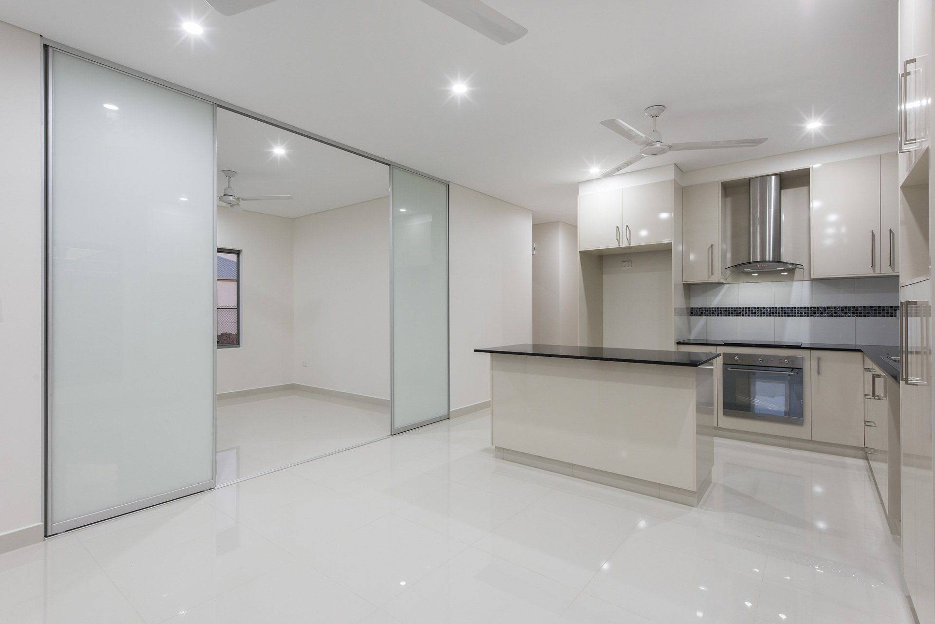 An empty kitchen with white cabinets and sliding glass doors.