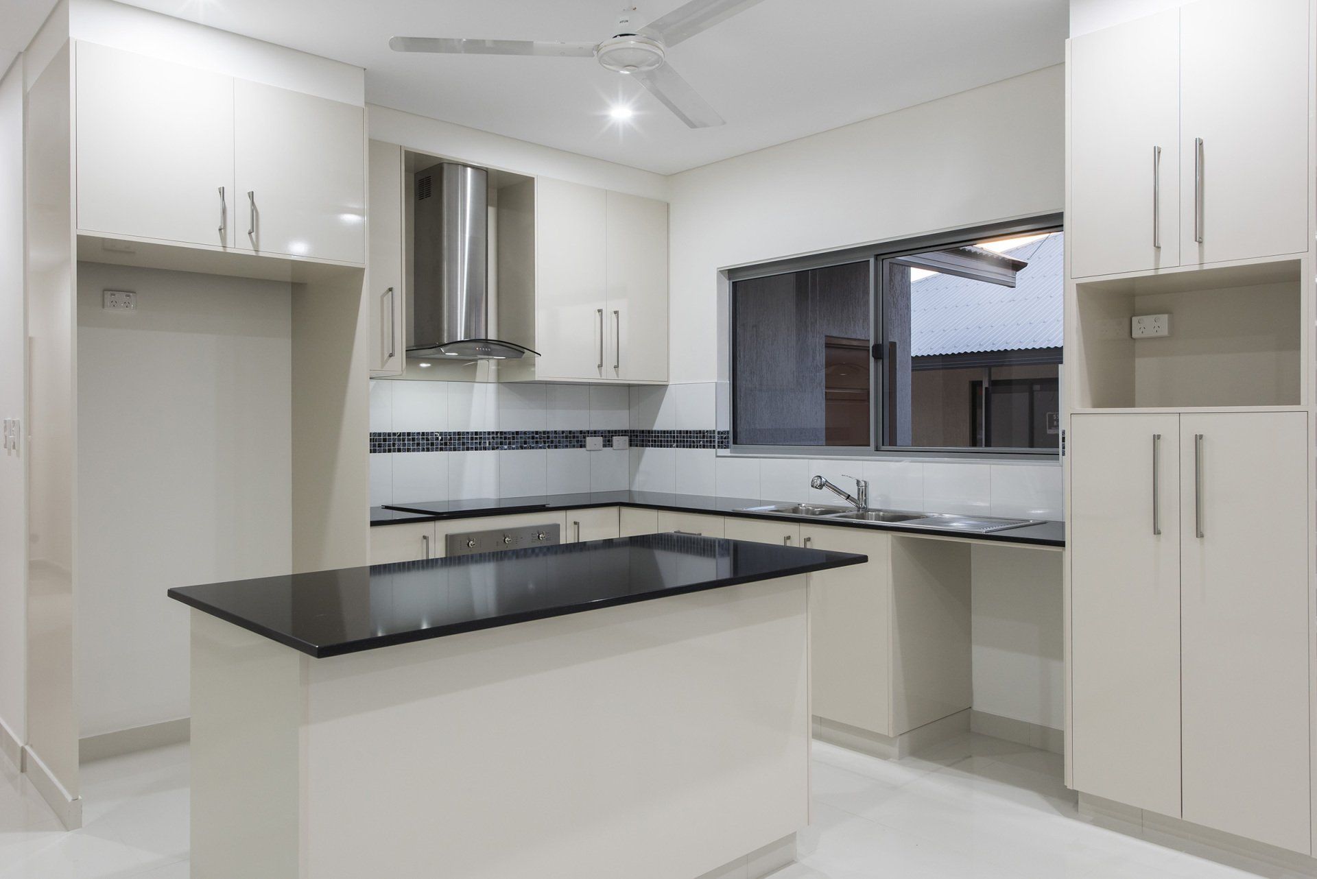 A kitchen with white cabinets and a black counter top