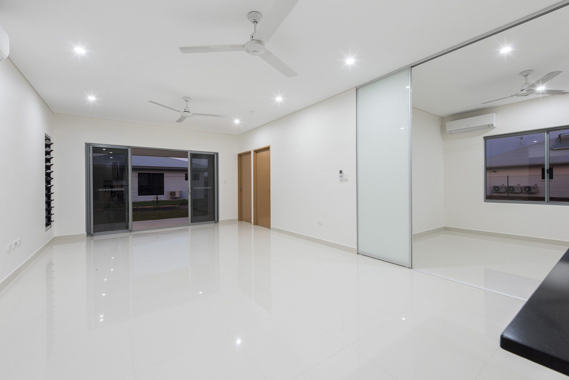 A large empty room with a ceiling fan and sliding glass doors.