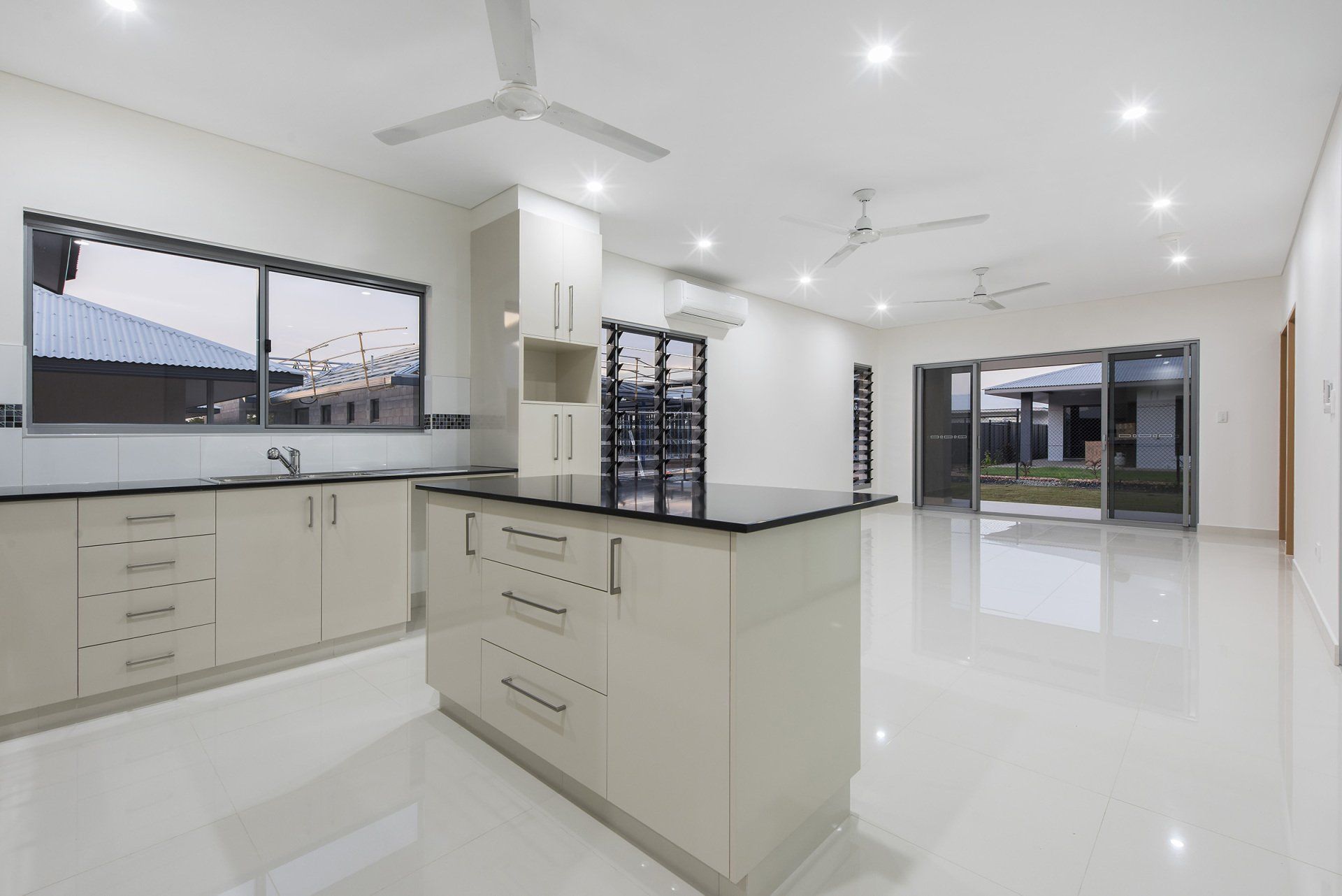An empty kitchen with white cabinets and black counter tops