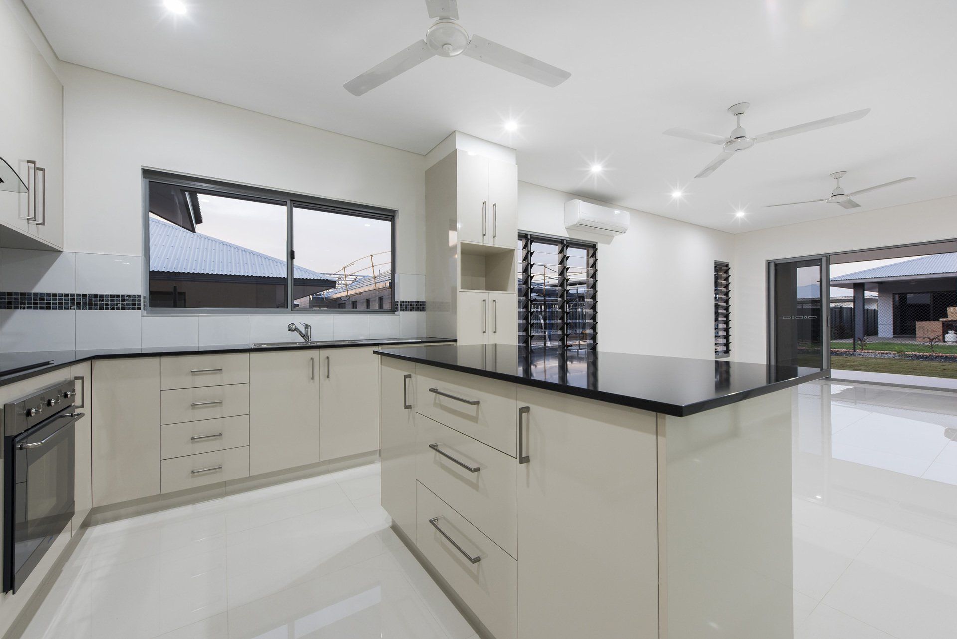 A kitchen with white cabinets and black counter tops and a ceiling fan.