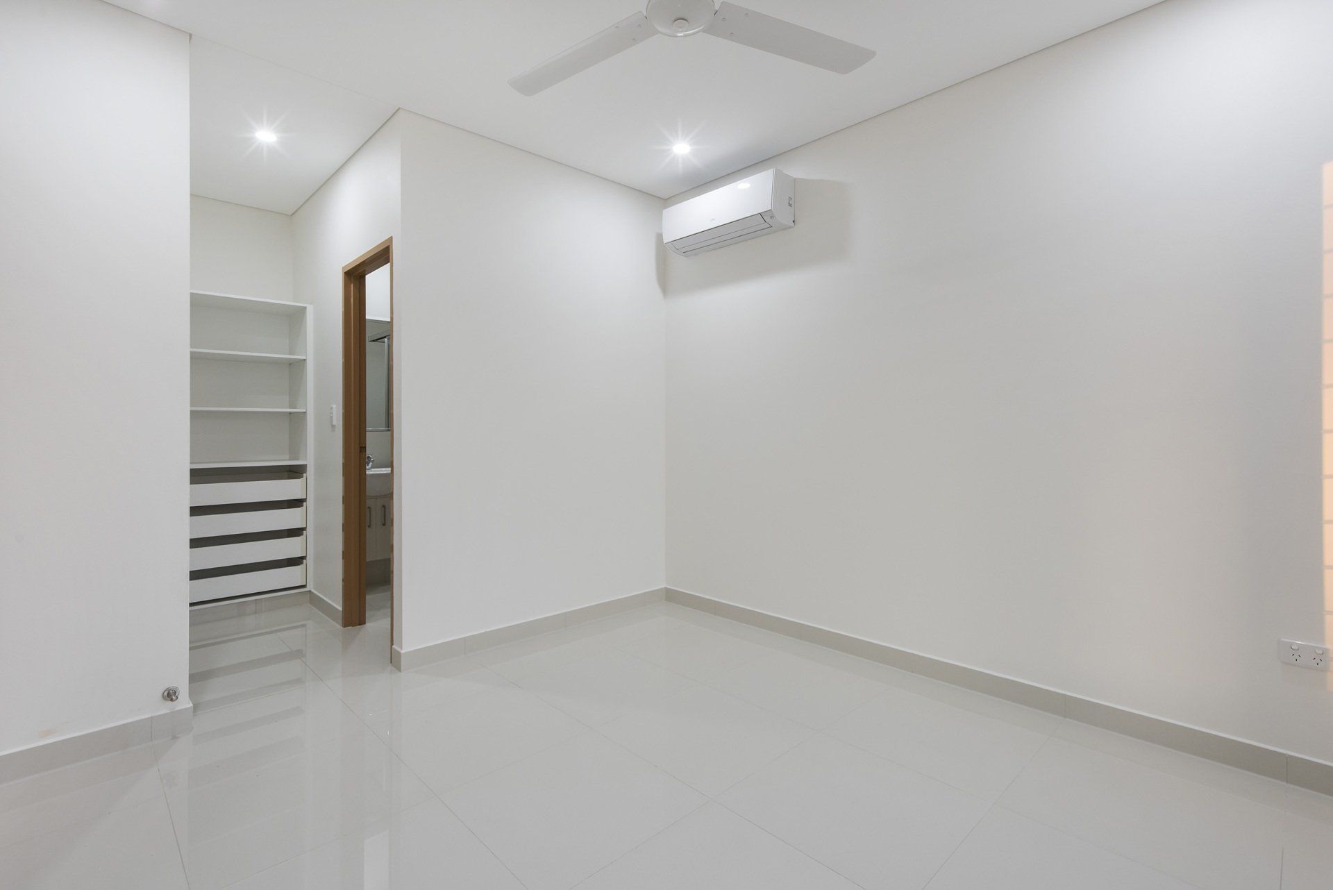 An empty room with white walls and a ceiling fan.