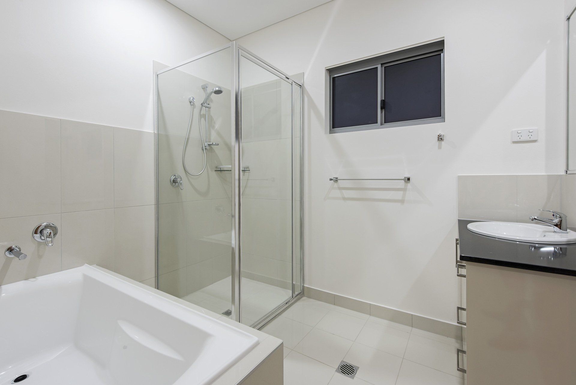 A bathroom with a bathtub , sink , shower and window.