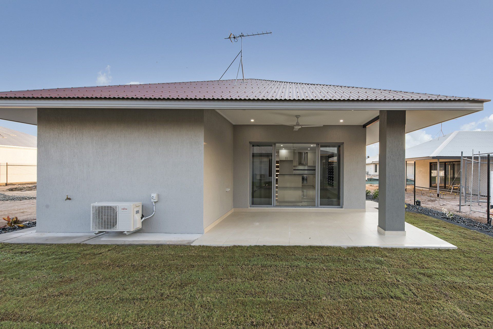 A small house with a red roof and a patio in front of it