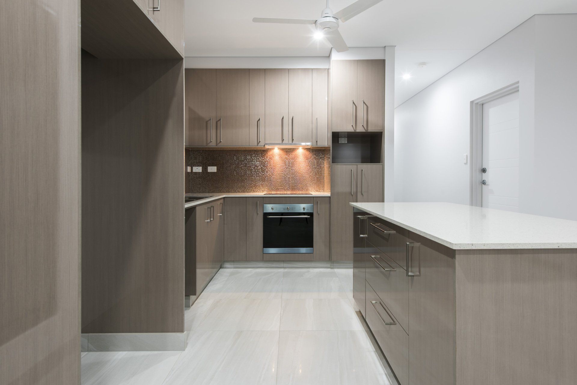 An empty kitchen with brown cabinets and white counter tops