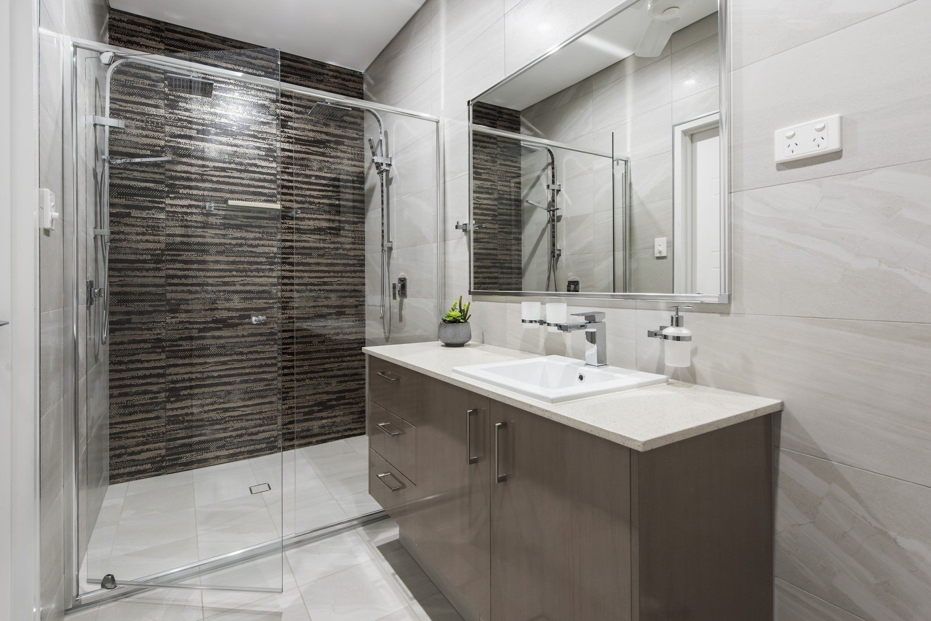 A bathroom with a sink , mirror and walk in shower.
