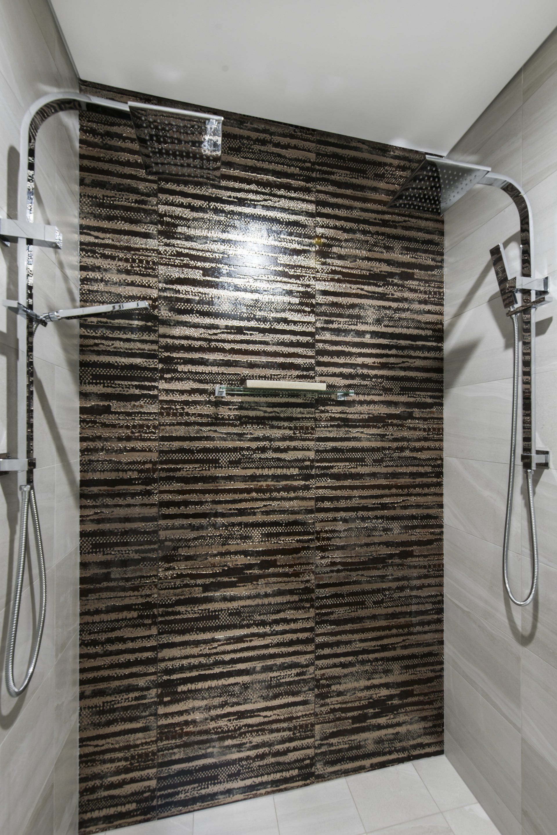 A shower with two shower heads and a stone wall.