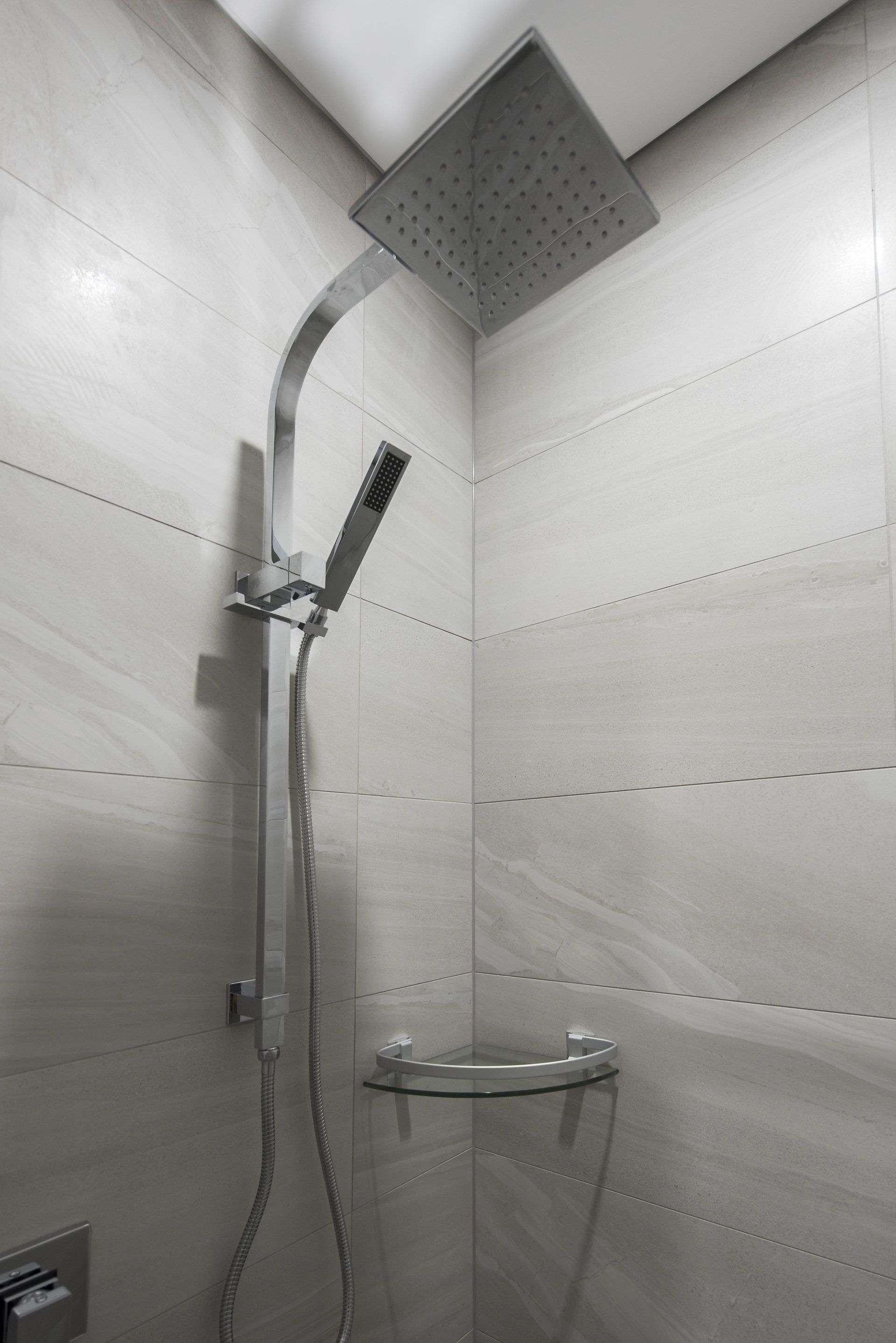 A shower head is hanging from the ceiling in a bathroom.