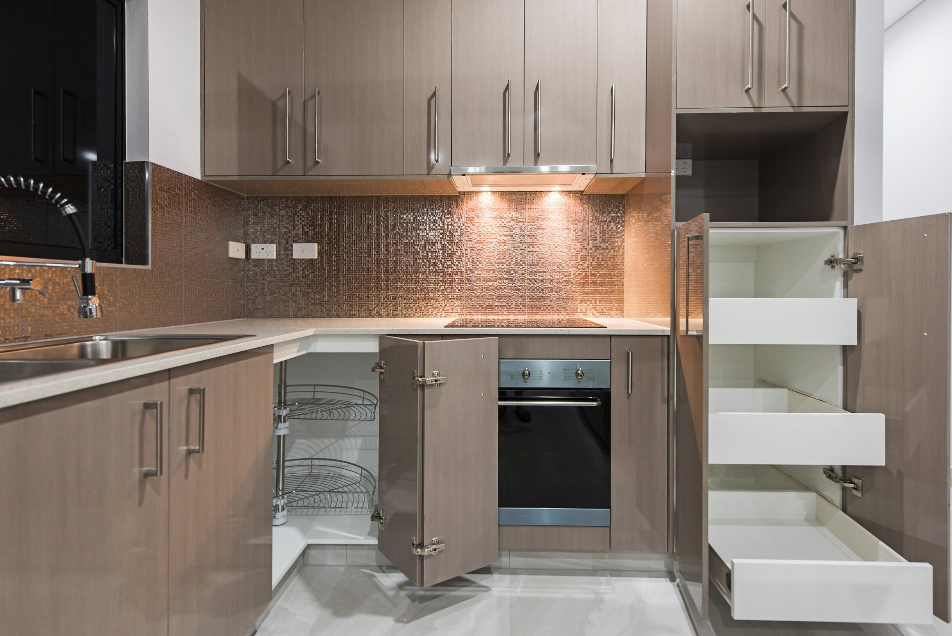 A kitchen with a stove , sink , drawers and cabinets open.