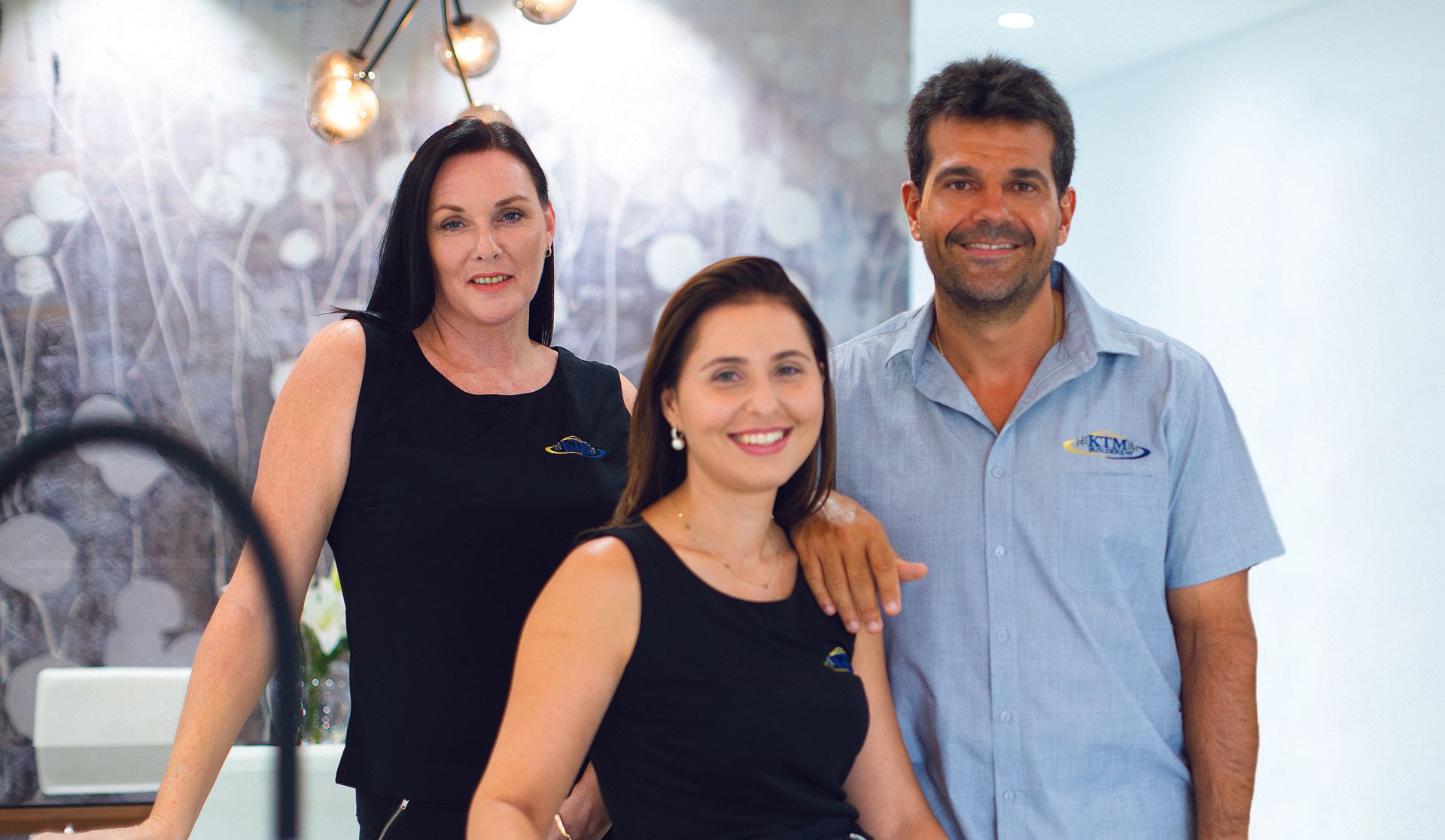 A man and two women are posing for a picture in a kitchen.