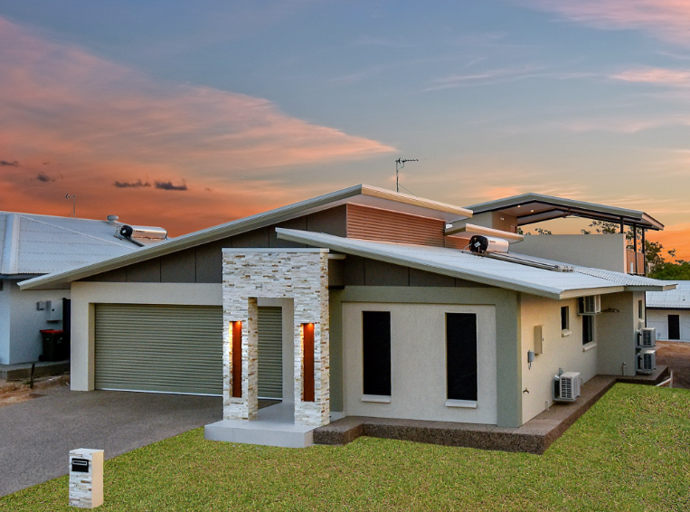 A house with two garages and a sunset in the background