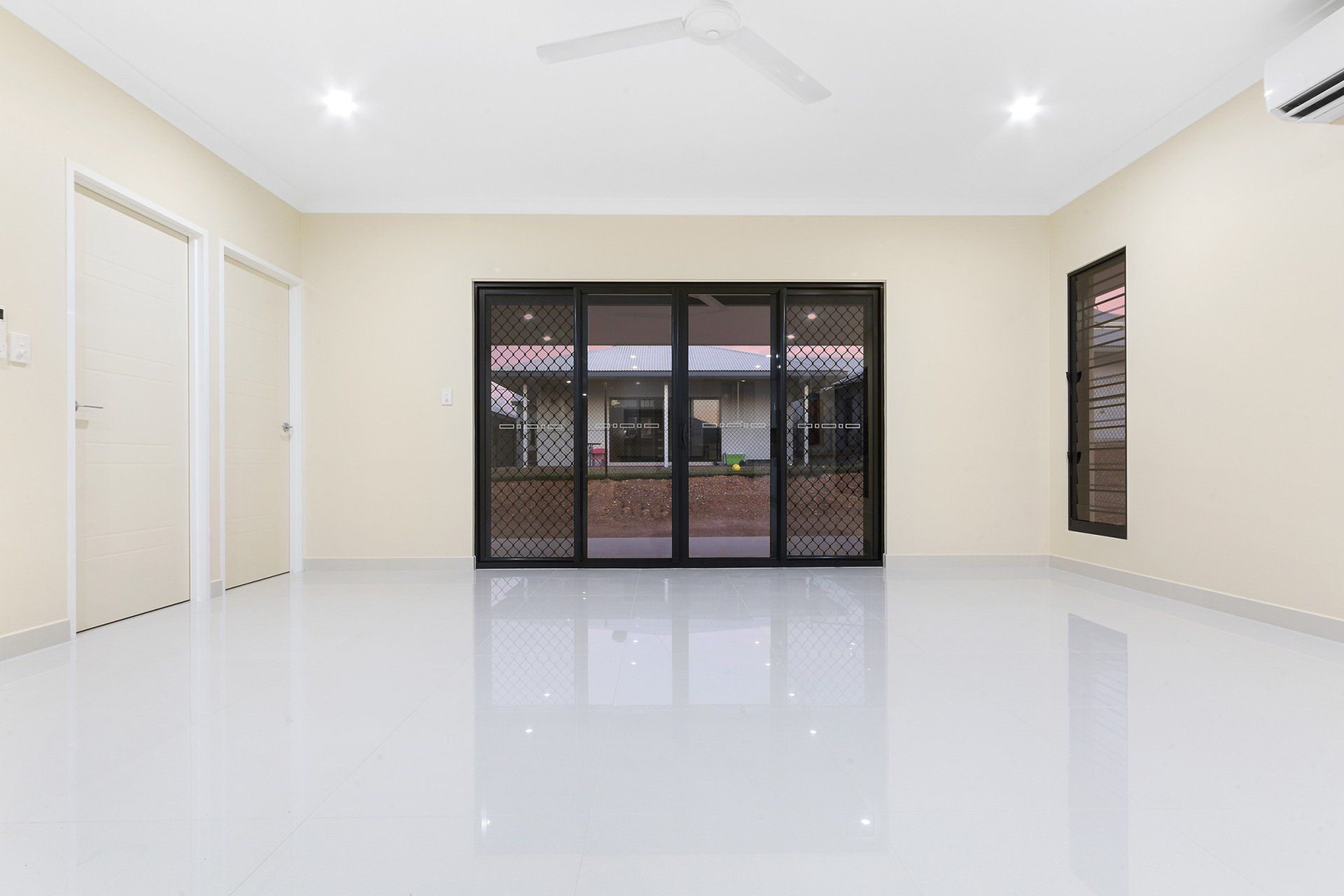 An empty living room with sliding glass doors and a ceiling fan.