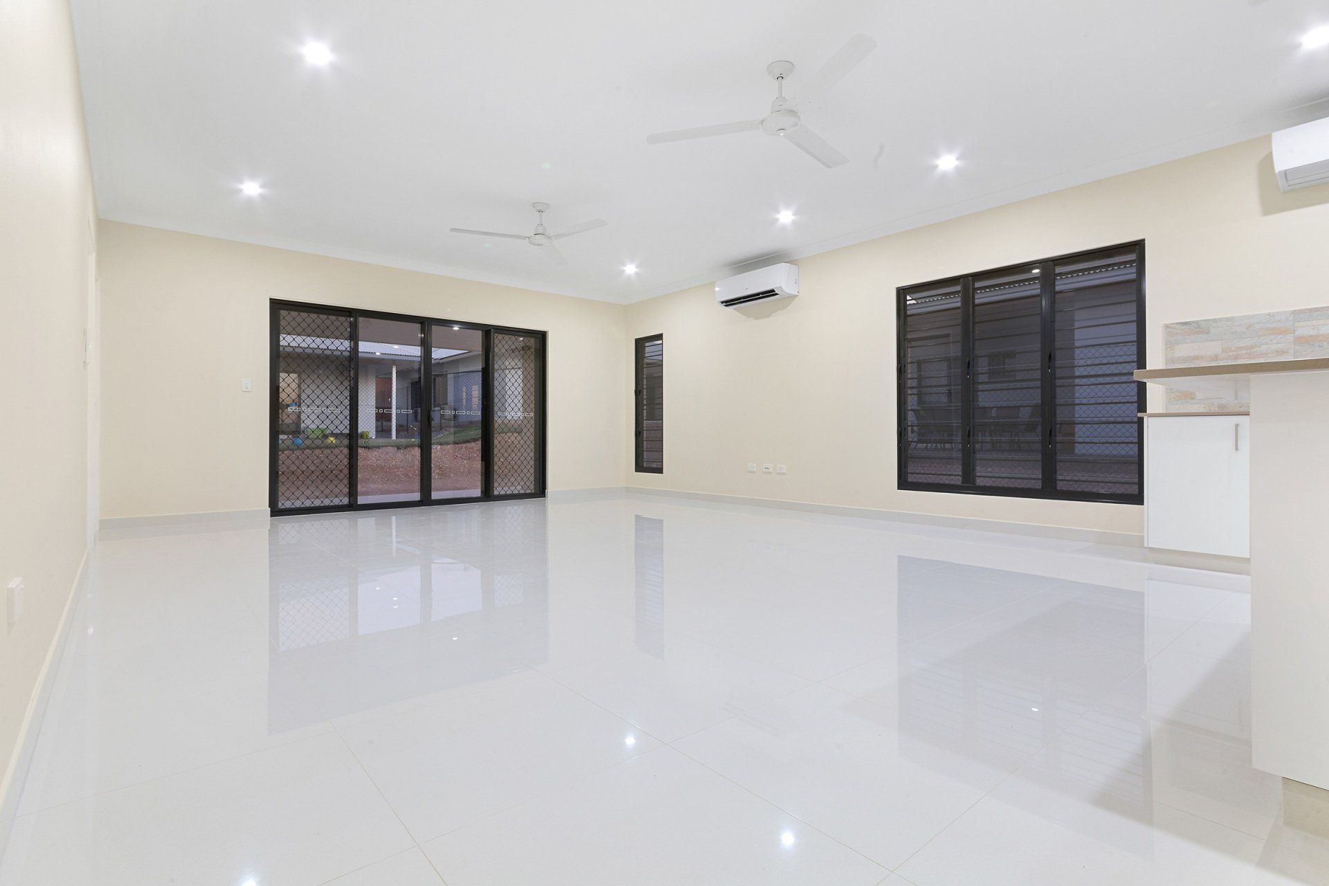 A large empty room with a ceiling fan and sliding glass doors.