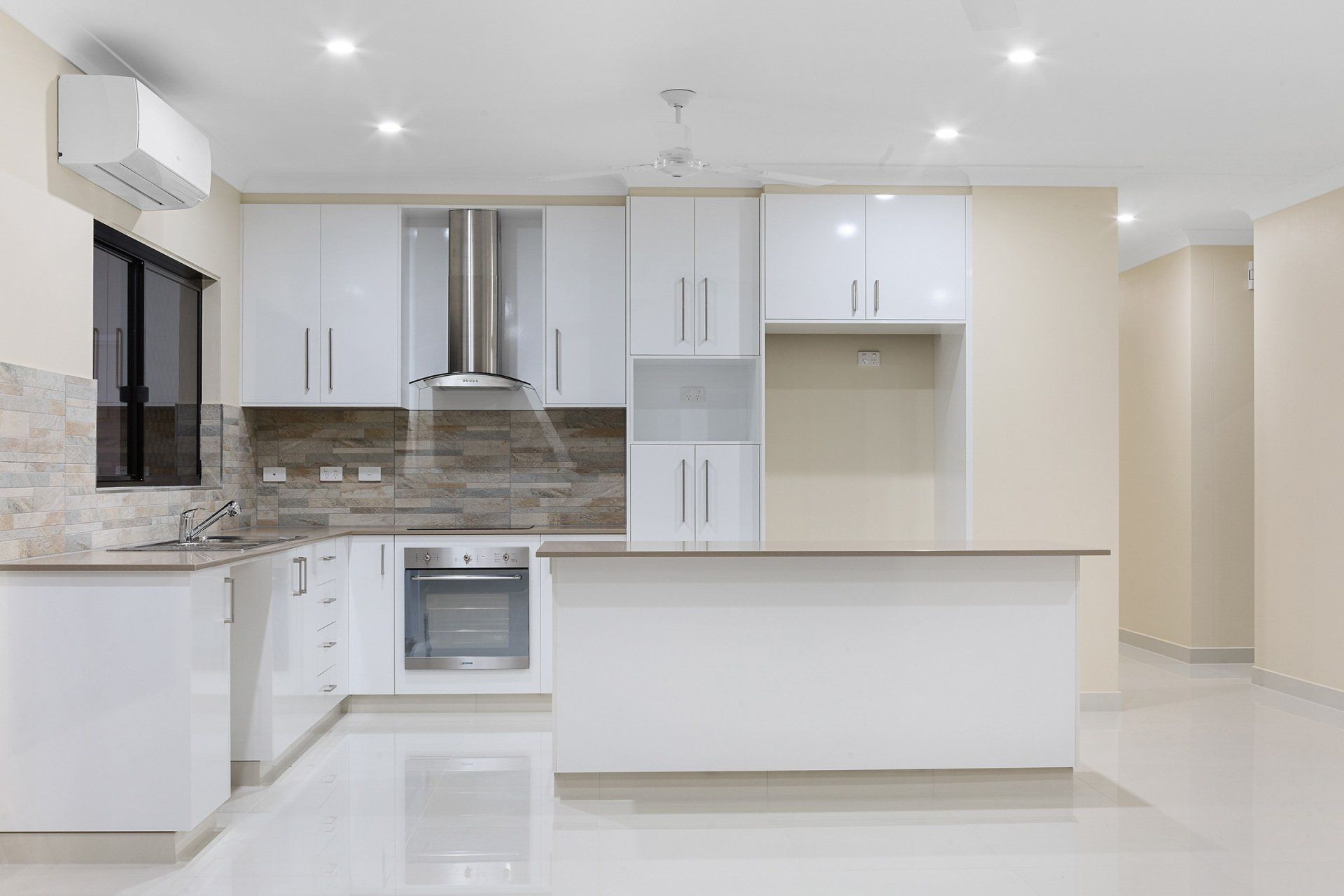An empty kitchen with white cabinets , a stove , and a refrigerator.