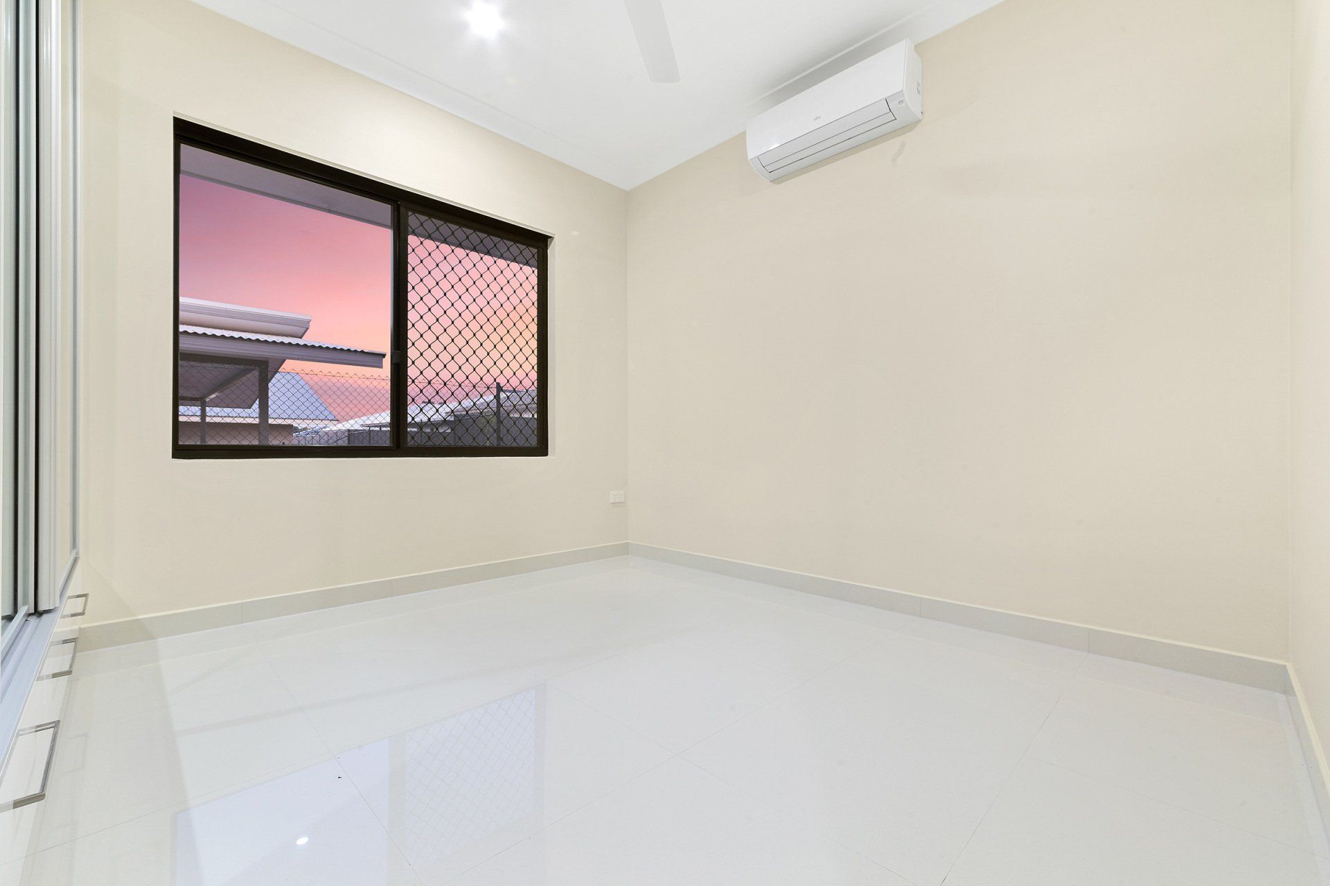 An empty room with a large window and a ceiling fan.